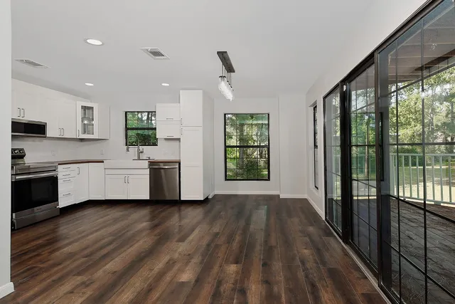 a open kitchen with white cabinets a sink and wooden floor