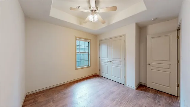 an empty room with windows and ceiling fan