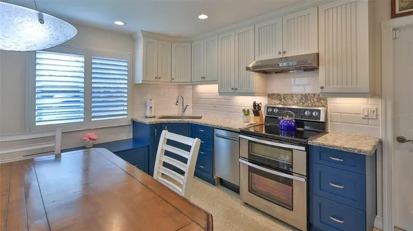 a kitchen with stainless steel appliances granite countertop a sink a stove and a wooden floors