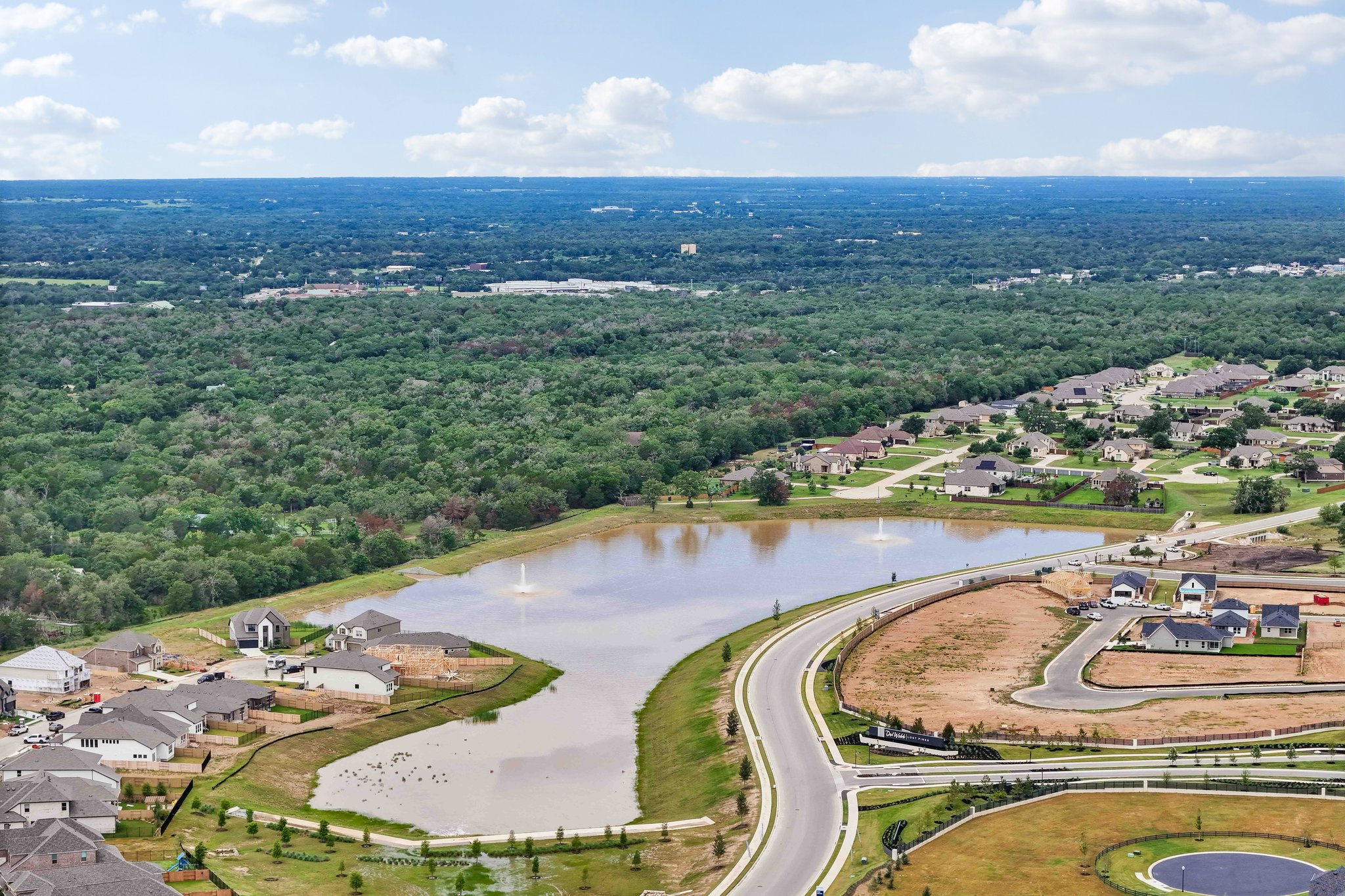 130 Firethorn Loop Bastrop, TX 78602 - Photo 34 of 38 Expansive aerial rendering showcasing a residential community featuring a prominent central pond with fountains