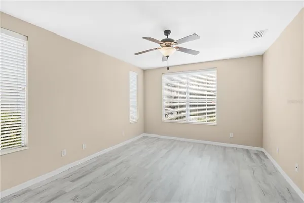 a view of empty room with wooden floor and fan