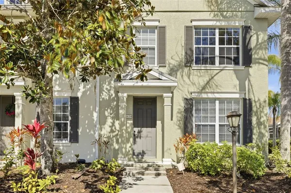 front view of a brick house with a large windows and a potted plant