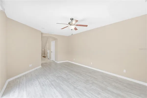 a view of an empty room with chandelier fan and wooden floor