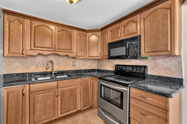 a kitchen with granite countertop stainless steel appliances a stove a sink and a microwave