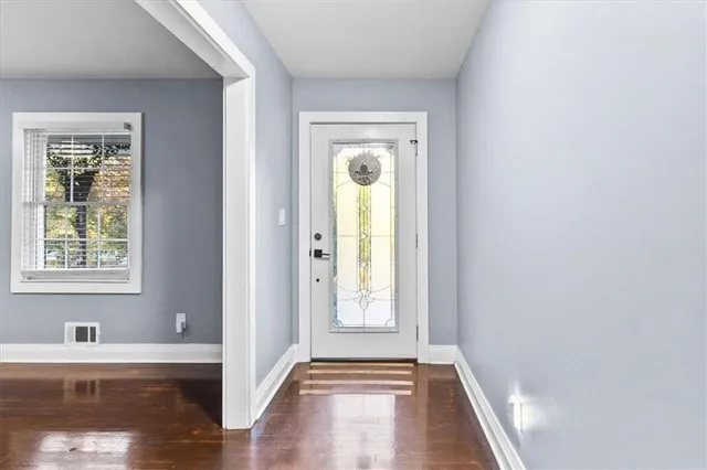 a view of hallway with window and wooden floor