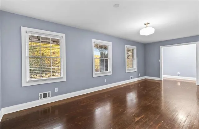 a view of an empty room with wooden floor and a window