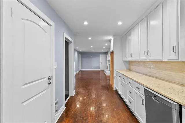 a hallway with granite countertop white cabinets and stainless steel appliances
