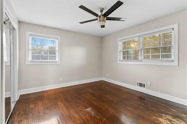 a view of empty room with wooden floor and fan