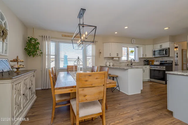 a kitchen with stainless steel appliances kitchen island granite countertop a table chairs and a refrigerator