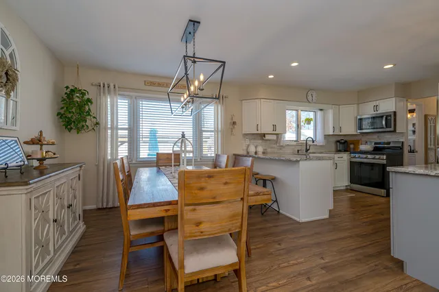 a kitchen with stainless steel appliances kitchen island granite countertop a table chairs and a refrigerator