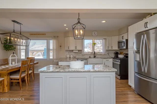 a kitchen with granite countertop a refrigerator a stove a dining table and chairs