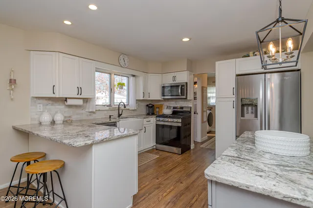 a kitchen with stainless steel appliances granite countertop a refrigerator a stove a sink dishwasher and a refrigerator with wooden floor