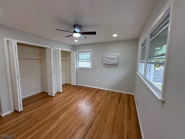 a view of empty room with wooden floor and fan