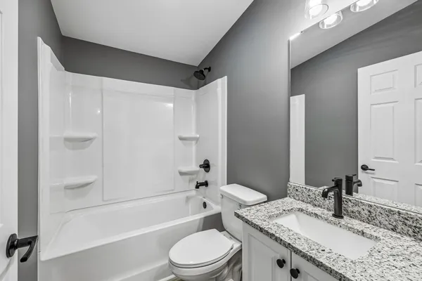 a bathroom with a granite countertop sink a toilet and shower