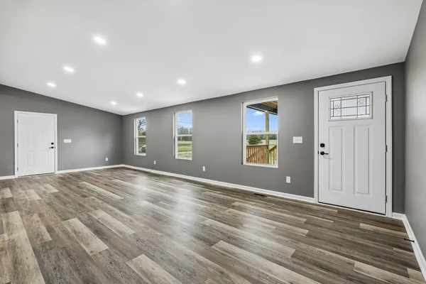 a view of an empty room with wooden floor and windows