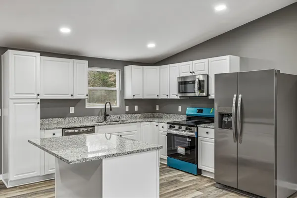 a kitchen with stainless steel appliances granite countertop a sink a stove a refrigerator and cabinets
