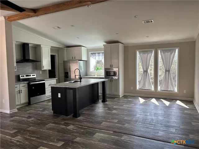 a large kitchen with kitchen island granite countertop a stove top oven a sink dishwasher a dining table and chairs with wooden floor