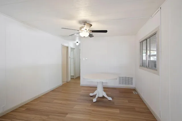 a view of a room with wooden floor and a ceiling fan