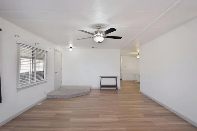 a view of an empty room with a window and a kitchen