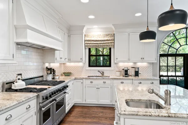 a kitchen with stainless steel appliances granite countertop a sink a stove and a wooden floors