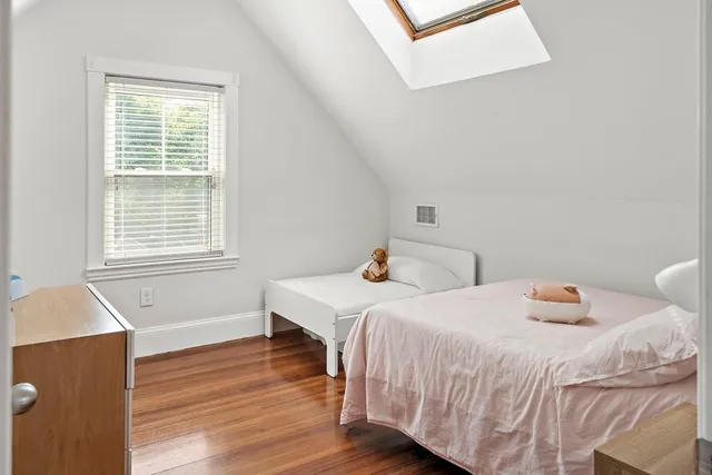 a bedroom with two beds and wooden floor