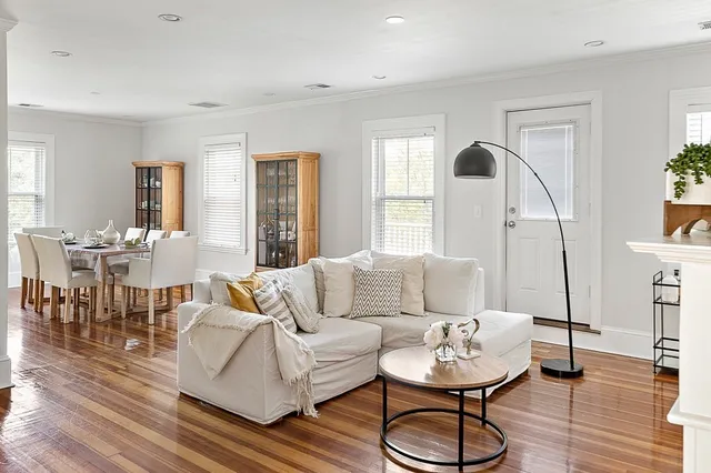 a living room with furniture and a dining table with wooden floor