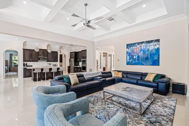 a living room with furniture kitchen view and a chandelier