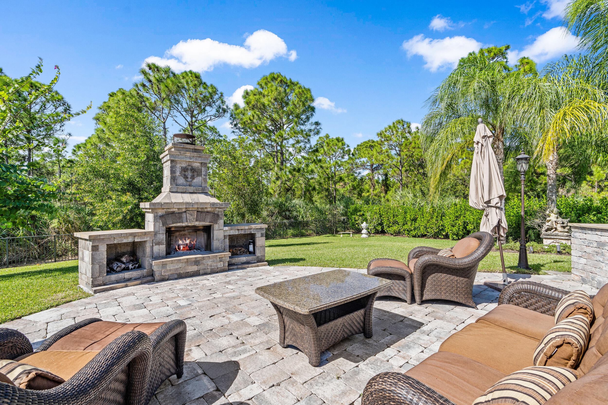 19240 Southeast Hidden Bridge Court Jupiter, FL 33458 - Photo 34 of 42 a view of a patio with couches table and chairs with potted plants and big yard