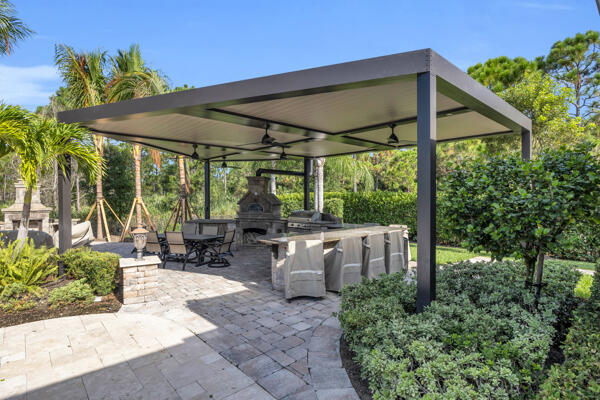 19240 Southeast Hidden Bridge Court Jupiter, FL 33458 - Photo 39 of 42 a backyard of a house with table and chairs under an umbrella