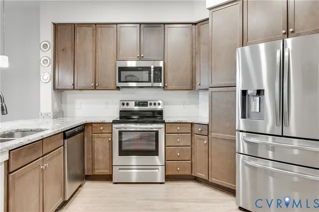 a kitchen with stainless steel appliances granite countertop a sink and a wooden floor