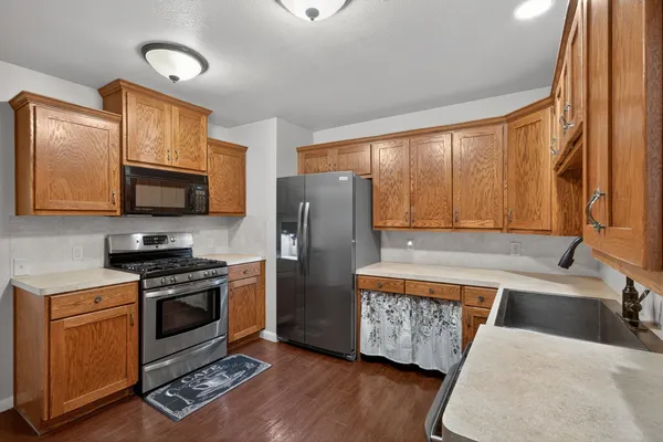 a kitchen with stainless steel appliances granite countertop a refrigerator a stove top oven a sink and dishwasher