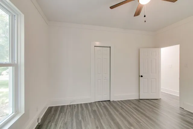 a view of an empty room with wooden floor and a window