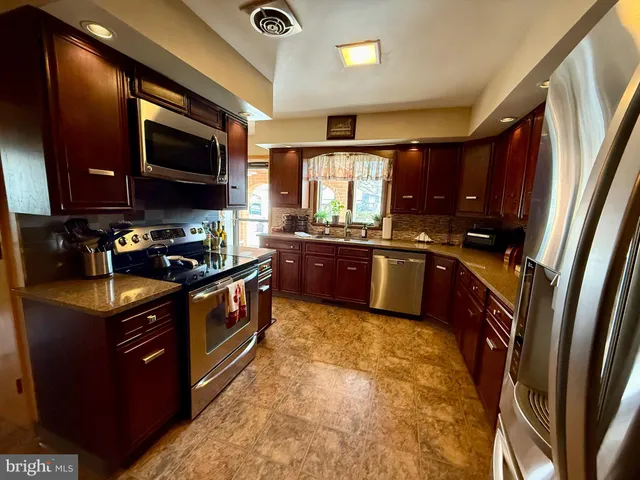 a kitchen with stainless steel appliances granite countertop wooden cabinets a sink and a stove