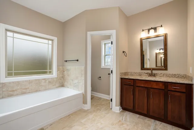 a bathroom with a tub a sink and a mirror