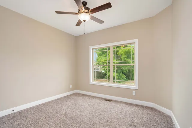 an empty room with a window and a fan