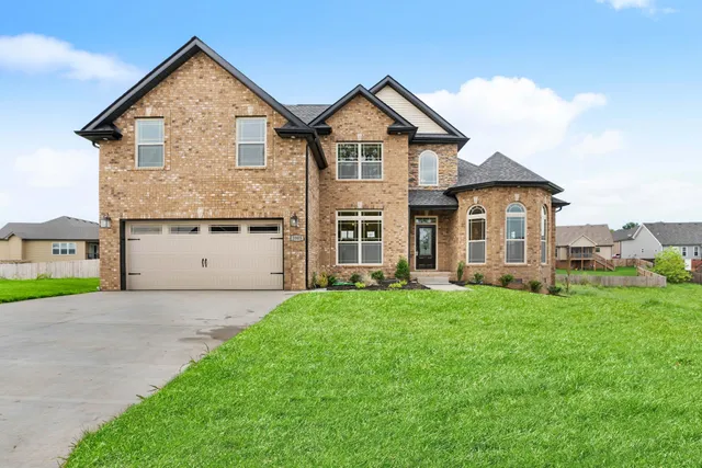 a view of a yard in front of a house with large windows