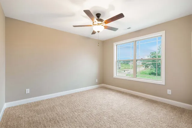 an empty room with ceiling fan and window