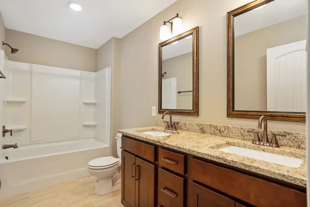 a bathroom with a granite countertop sink toilet mirror and bathtub
