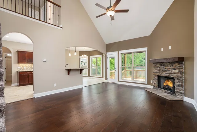 a view of an empty room with wooden floor and a fireplace