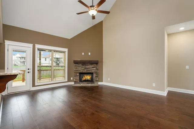 an empty room with wooden floor fireplace and windows