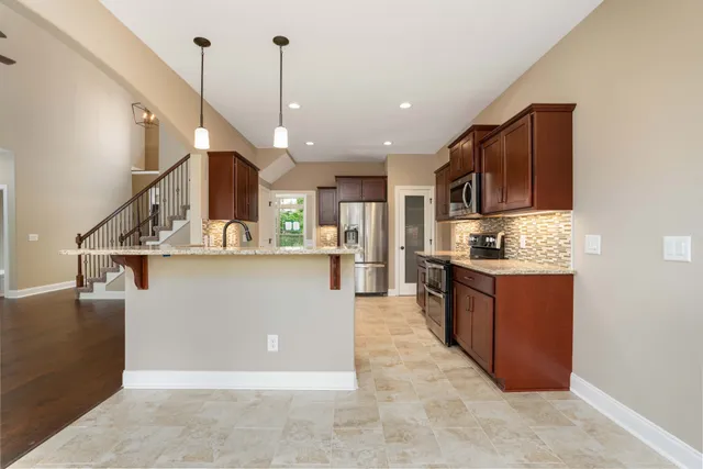 a large kitchen with stainless steel appliances kitchen island granite countertop a refrigerator a stove a sink and a dishwasher