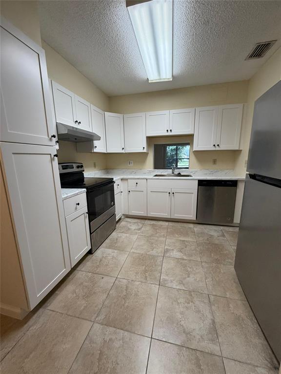7410 Woodmont Terrace, Unit 207 Tamarac, FL 33321 - Photo 3 of 20 a kitchen with a sink a stove top oven and white cabinets