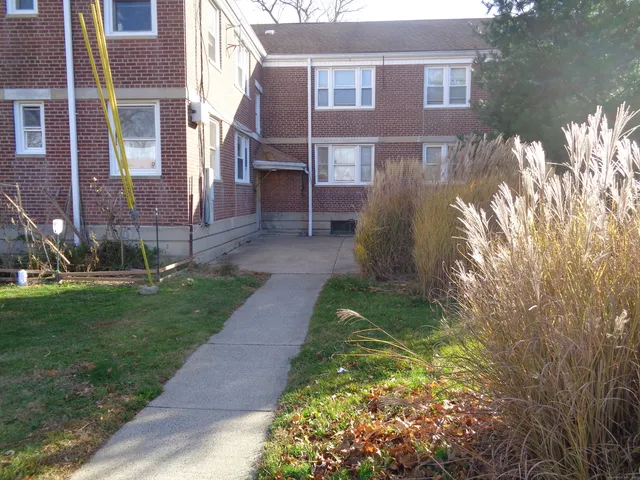 a view of a brick house with a yard and plants
