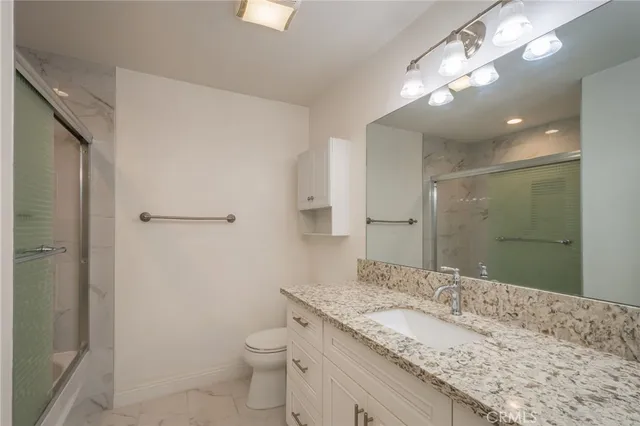a bathroom with a granite countertop sink a toilet and a mirror