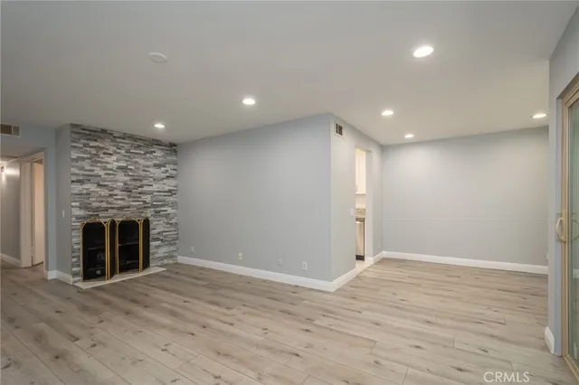 an empty room with wooden floor fireplace and windows