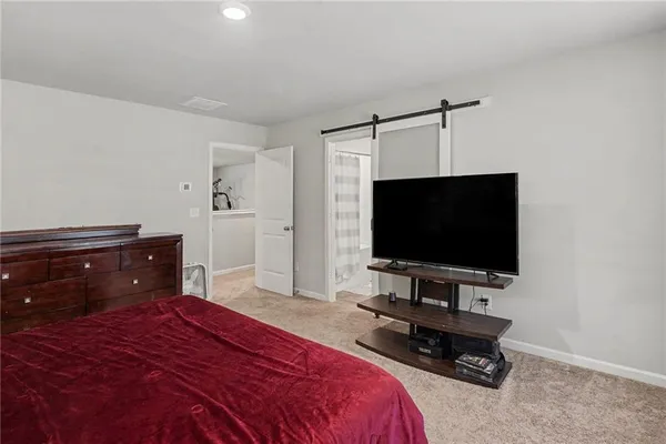 a bedroom with a bed and a flat tv screen on dresser