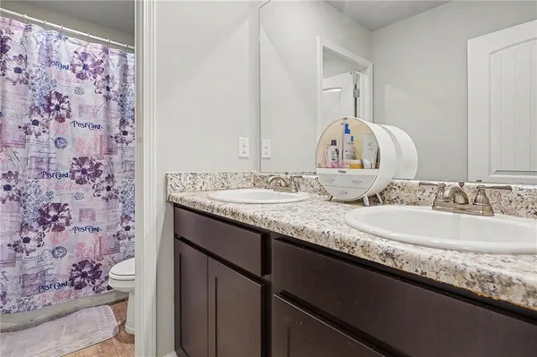 a bathroom with a granite countertop double vanity sink and a mirror