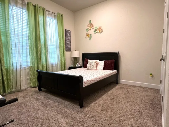 a large bed sitting in a bedroom next to a window and a chandelier