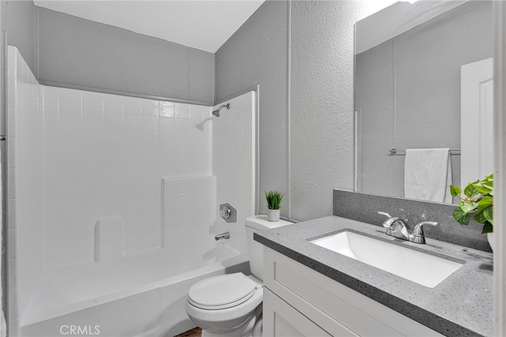 8074 Mira Mar Road Phelan, CA 92371 - Photo 20 of 49 a bathroom with a granite countertop sink toilet a mirror a shower and a bathtub