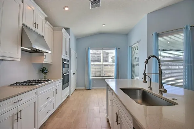 a kitchen with granite countertop white cabinets and stainless steel appliances